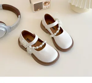 Close-up of white Mary Jane girl shoes with elegant pearl beads and mesh bow decoration