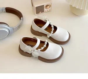 Close-up of girls white Mary Jane shoes with pearl chains and lace bows decoration