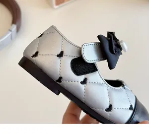 Détail de ballerines Mary Jane argentées avec surpiqûres en cœur et nœud en perle