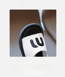 Detail view of child's white leather sandal featuring black LU lettering and round toe