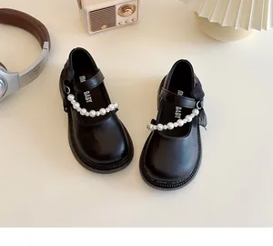 Detail of girl's black Mary Jane shoes featuring pearl straps and mesh bow accents