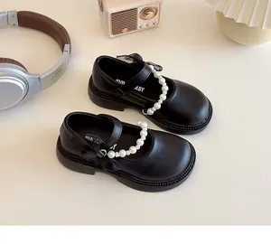 Detail of girls black Mary Jane shoes featuring pearl chain and mesh bow accents