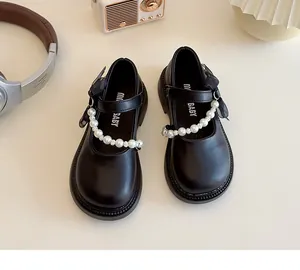 Detail of girls' black Mary Janes with pearl strap and sheer bow decoration