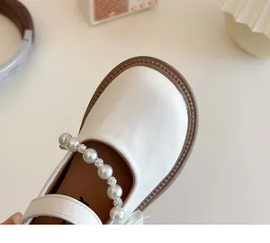 Detailed macro view of beige Mary Jane shoes with pearl and rhinestone beaded strap