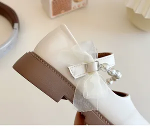Detail of girls' cream Mary Janes featuring a sheer bow and elegant pearl strap