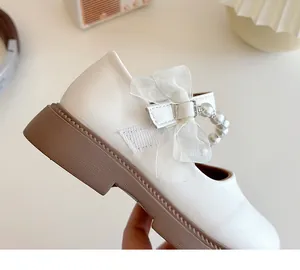Detail of girls' white Mary Jane shoes featuring a gauze bow and pearl strap accents