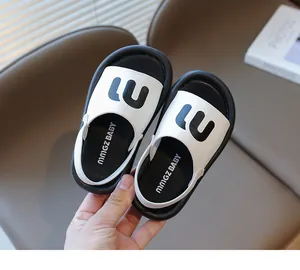 Close-up detail of girls' black and white sandals with m logo and elastic backstrap