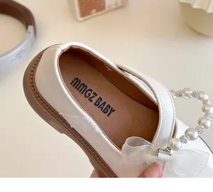 Close-up of white girls princess shoes with pearl beads and soft mesh bow decoration