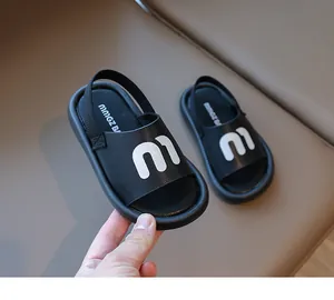 Close-up of black toddler sandals featuring white logo print and thick EVA sole