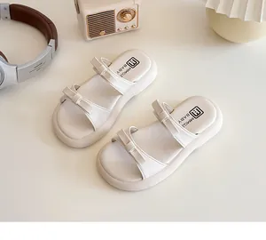 Close-up of cream beige kids slide sandals with double bow straps and soft thick soles