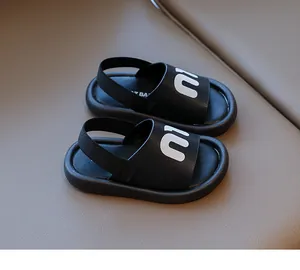 Detail view of black kids' sandals featuring white M logo and elastic heel strap