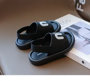 Detail of black children's sandals with letter 'n' and elastic heel strap on leather base