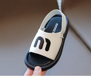 Detailed close-up of white leather kids sandals with stylish m logo and thick black soles