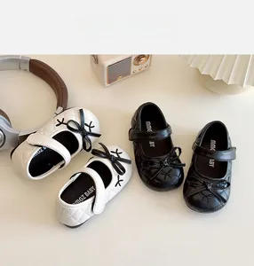 Vista dall'alto di scarpe Mary Jane trapuntate con fiocco per bambine in nero e bianco