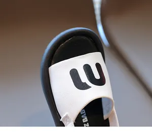 Detailed close-up of white leather straps with black letters on kid's fashion sandals