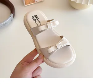 Close-up of cream children sandals featuring decorative bows and soft branded footbed