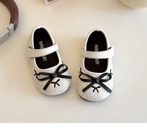 Dettaglio scarpe Mary Jane bianche per neonata con fiocco nero e velcro