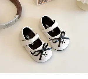 Dettaglio di scarpe Mary Jane trapuntate bianche per bambina con fiocco nero e velcro
