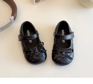 Dettaglio delle scarpe Mary Jane nere da bambina con trama trapuntata e fiocco elegante