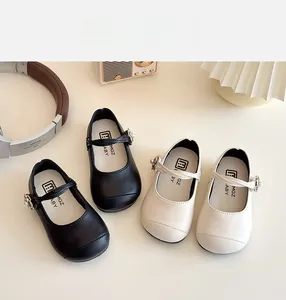 Detail of kids Mary Jane shoes in black and beige with pearl buckles and velcro straps