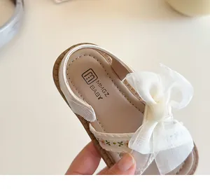 Gros plan de sandales crème pour filles avec nœud en tulle et broderie florale détaillée