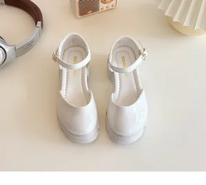 Details von weißen Mary Jane Halbschuhen aus Lackleder mit dicker Sohle und Metallschnalle