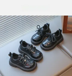 Detail of children's black oxfords with lace-up and velcro closure on a gray bench