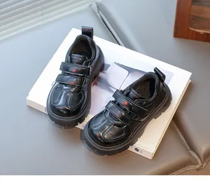 Detail of kids black loafers with double hook and loop straps and chunky rubber sole