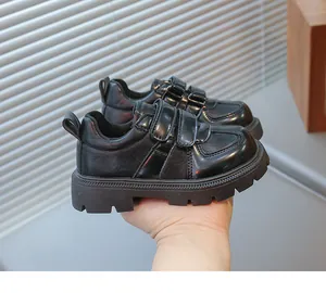 Detail view of children's black leather shoes featuring double hook-and-loop fasteners