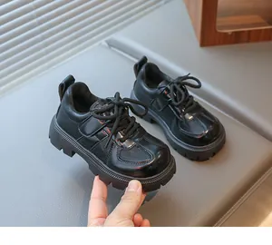 Detail view of black children's oxford shoes featuring glossy patent leather and thick soles
