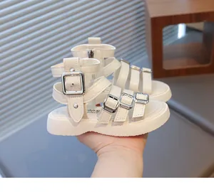 Detail of white girls' gladiator sandals with woven straps and silver buckle closures