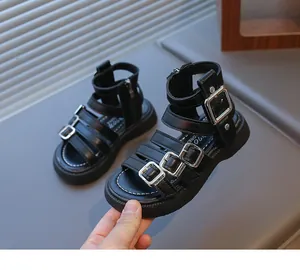 Detail of girls' black Roman sandals with silver buckles and white stitching details