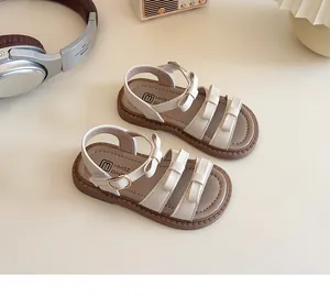 Dettaglio di sandali crema da bambina con tre fiocchi decorativi e fibbie dorate