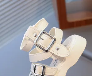 Close-up of beige platform sandals featuring silver buckles, studs and textured sole