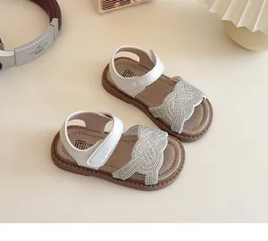 Vista superior de sandalias blancas con strass para niñas con tiras trenzadas y suela
