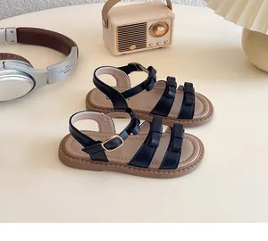 Dettaglio dei sandali per bambine in pelle nera con fiocchi eleganti e fibbie in metallo