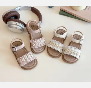 Dettaglio di sandali rosa e bianchi per bambine con rouches di pizzo e decorazioni a perla