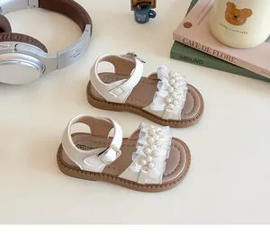 Dettaglio del sandalo avorio da bambina con volant in mesh, perle e strass scintillanti