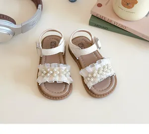 Dettaglio di sandali beige per bambine con ruches in pizzo, fiori di perle e velcro