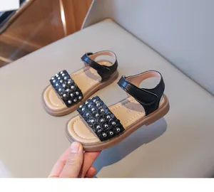 Détail de sandales noires pour filles avec perles argentées et bride velcro