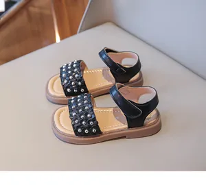 Gros plan sur les sandales noires pour filles avec fleurs en cuir, rivets et velcro