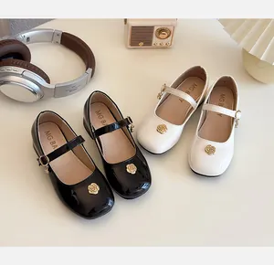 Dettaglio di scarpe Mary Jane da bambina in vernice nera e bianca con fibbie a rosa d'oro