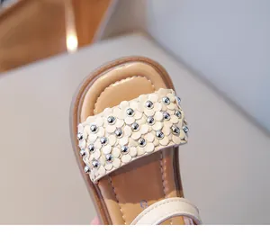 Gros plan de sandales beige en cuir pour filles avec fleurs 3D décoratives et clous argentés
