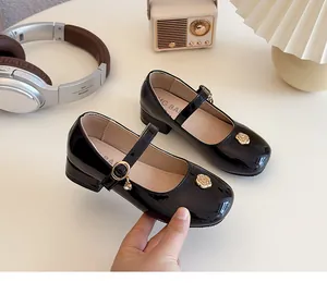 Dettaglio ravvicinato di scarpe Mary Jane in vernice nera da bambina con fibbie d'oro