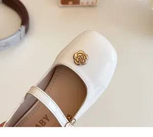 Dettaglio di scarpe bianche in vernice per bambine con fibbia a fiore di camelia