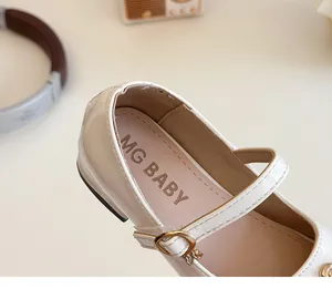 Dettaglio di scarpe Mary Jane color crema da bambina con fibbia dorata e suole morbide