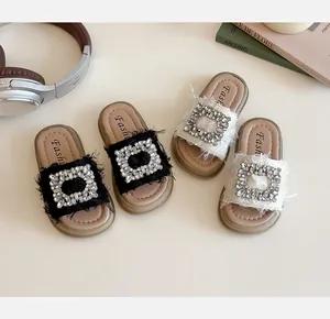 Detalle de sandalias para niña con hebilla de pedrería y bordes de tela deshilachados