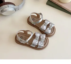 Gedetailleerd beeld van zilveren kindersandalen met strass strikken en metalen gespen