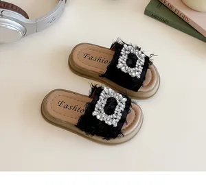Detalle de sandalias para niña con hebillas de strass y correas de tela deshilachada