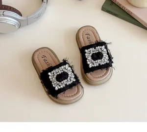 Primer plano de sandalias negras para niña con flecos y hebilla cuadrada de diamantes
